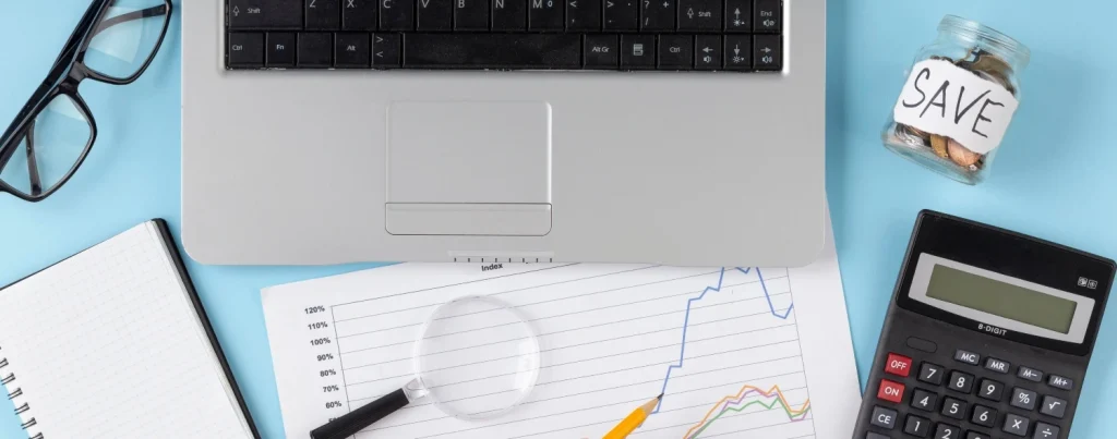 Persona calculando sus finanzas personales en un escritorio con gráficos financieros, calculadora y laptop, simbolizando la inteligencia financiera.